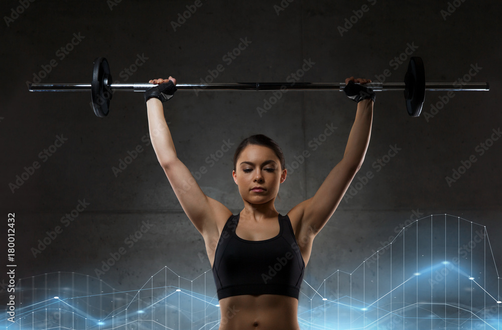Naklejka premium young woman flexing muscles with barbell in gym