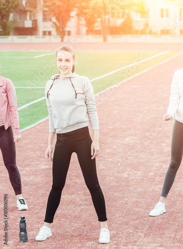 Energetic girl friends on a fitness training on a park background. Sport and stretches concept. Copy space.