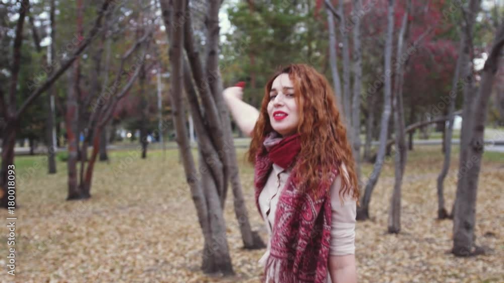 Cheerfulyoung woman with red hair in fall forest looking around having fun smiling in beautiful colorful forest foliage. Slow motion. 3840x2160 Cheerfulyoung woman with red hair in fall forest looking around having fun smiling in beautiful colorful forest foliage. Slow motion. 3840x2160