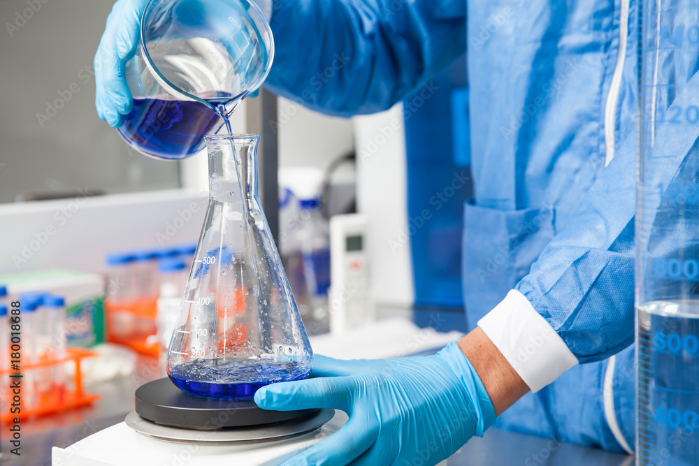 Young male scientist working with an stirrer at laboratory dressed in blue Young male scientist working with an stirrer at laboratory dressed in blue