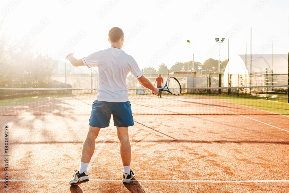 Man playing tennis in the morning in sunlight Man playing tennis in the morning in sunlight