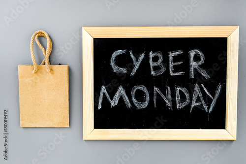 Words cyber monday written on blackboard and paper bags for shopping on grey background top view