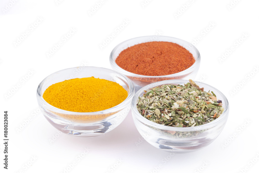 Ground turmeric, paprika and italian herbs in glass bowls isolated on white background Ground turmeric, paprika and italian herbs in glass bowls isolated on white background