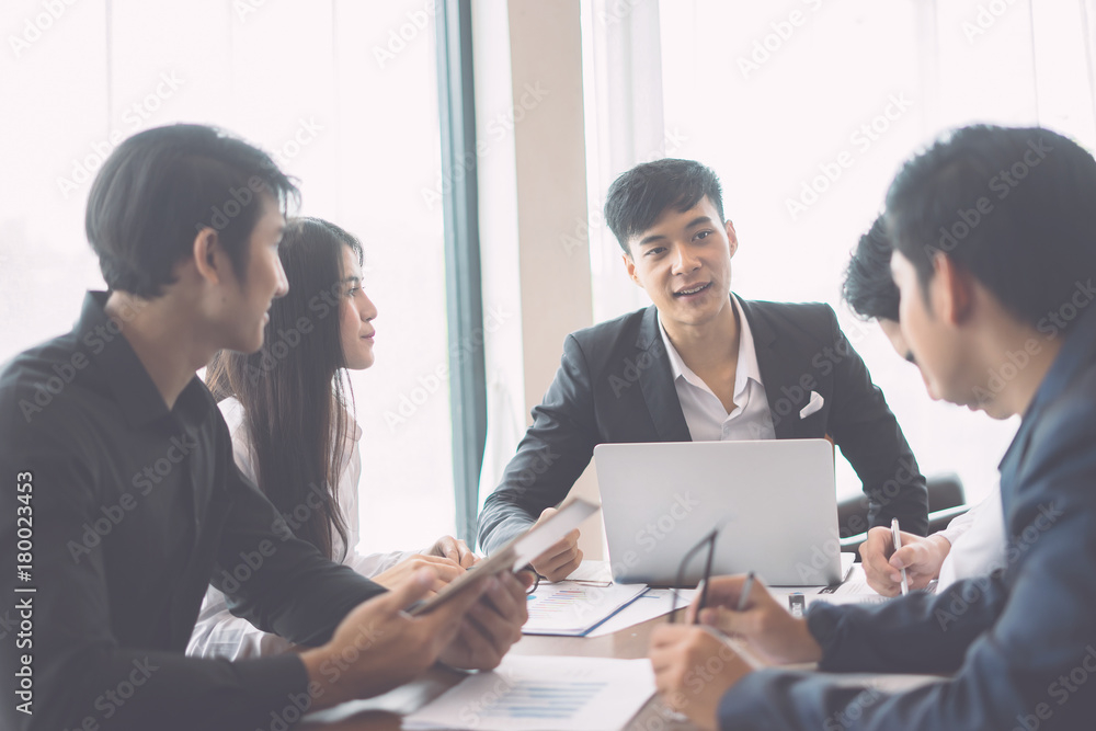 Asian Young man discussing market research with colleagues in a meeting. Business Team of young professionals having a meeting in conference room looking at documents. agreement and hiring concept Asian Young man discussing market research with colleagues in a meeting. Business Team of young professionals having a meeting in conference room looking at documents. agreement and hiring concept