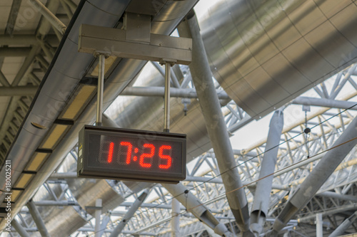 Digital LED clock with red light hanging on the ceiling for time telling in the airport or train station,The Subway , with many line of lights nearby ,slective focus vintage color