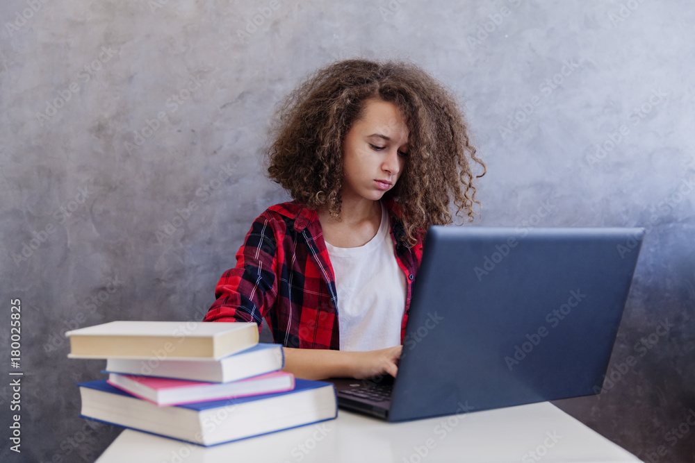 Curly hair teen girl websurfing internet on laptop at home Curly hair teen girl websurfing internet on laptop at home