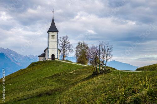 Jamnik, Slovenia - The beautiful church of St. Primoz in Slovenia near Jamnik with Julian Alps at background