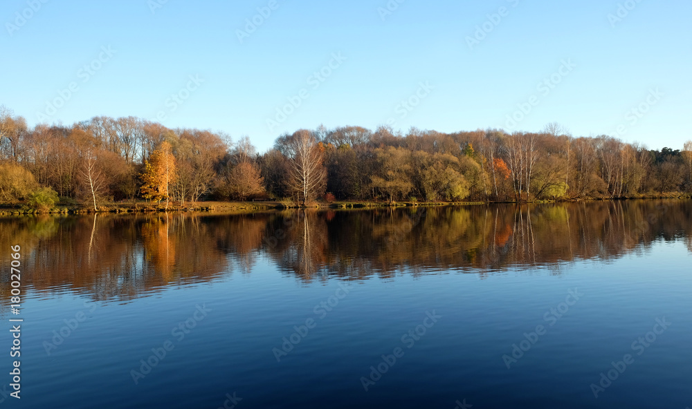 Beautiful countryside landscape with park after river under clear blue sky in late autumn