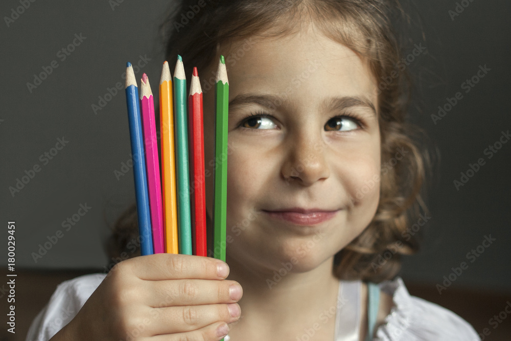 Little artist slyly looks at colored pencils: she has a new creative idea for painting Little artist slyly looks at colored pencils: she has a new creative idea for painting