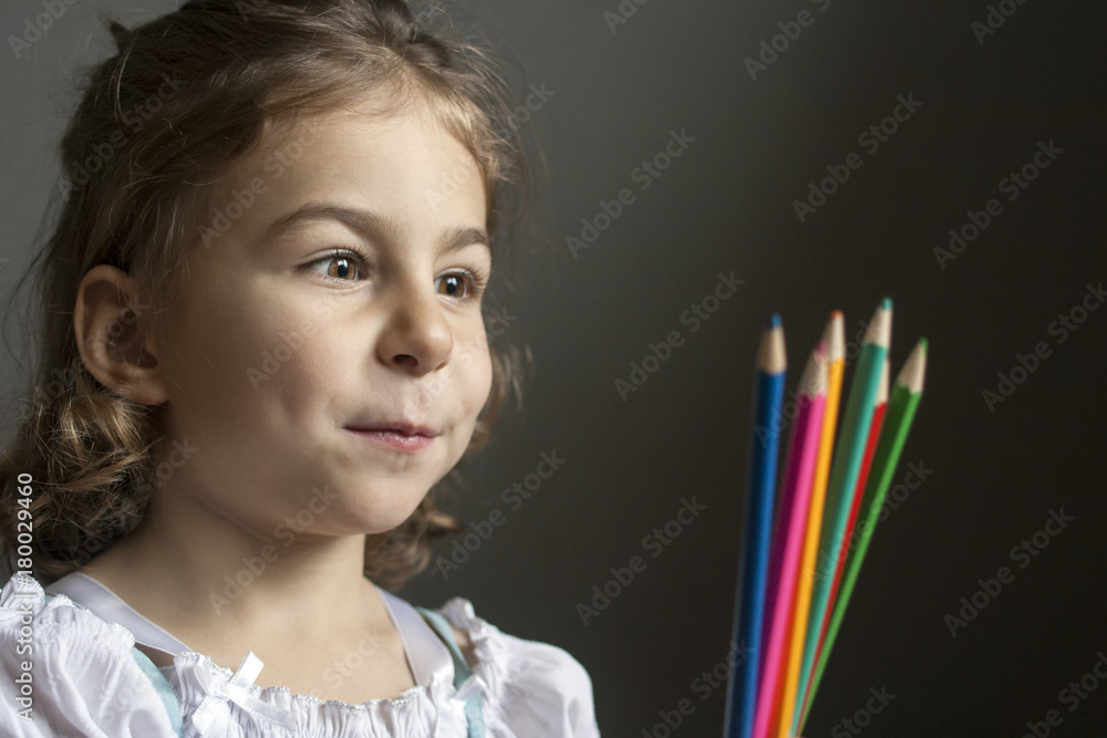 Little artist slyly looks at colored pencils: she has a new creative idea for painting Little artist slyly looks at colored pencils: she has a new creative idea for painting