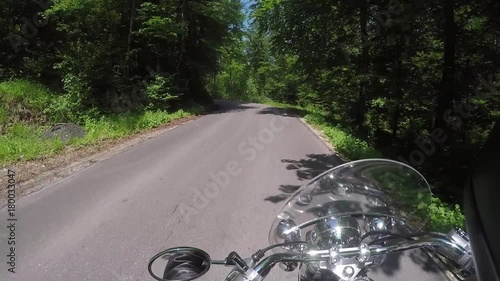 Classic motorcycle cruising down the road surrounded by forest, spring time, Croatia. photo