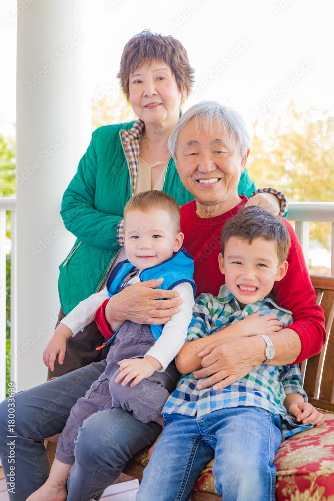 Senior Adult Chinese Couple Sitting With Their Mixed Race Grandchildren Senior Adult Chinese Couple Sitting With Their Mixed Race Grandchildren