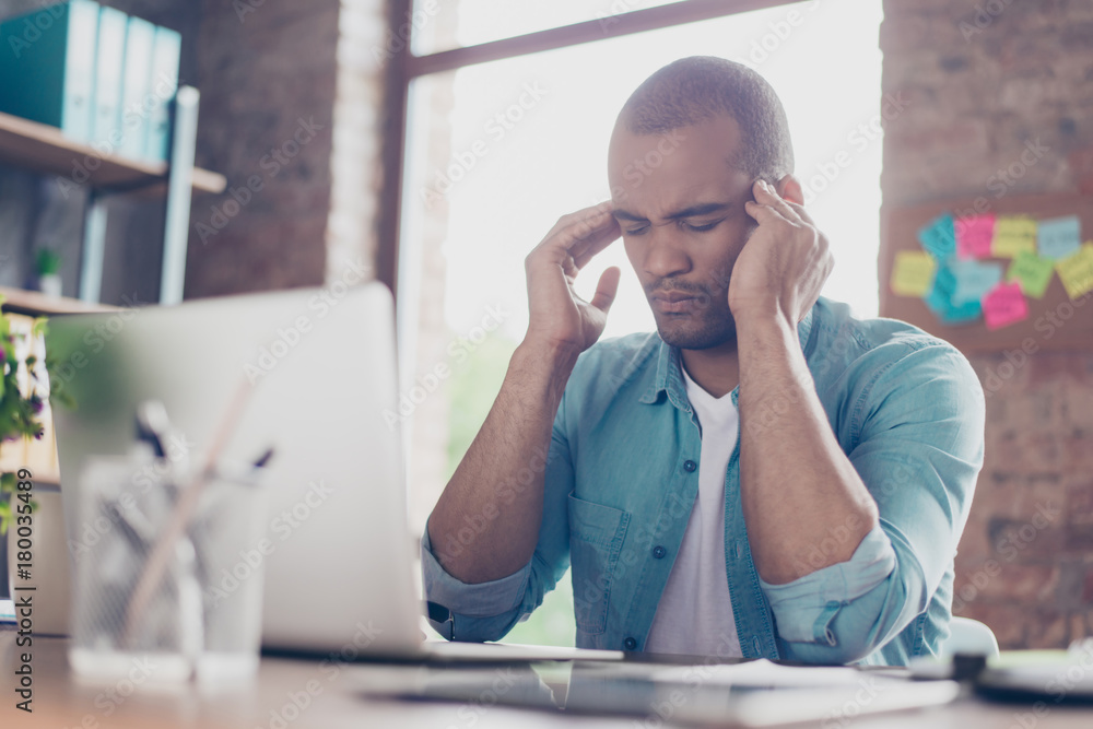 Overworked stressed freelancer is having headache and thinking how to end project. He is in a casual smart, at his home office Overworked stressed freelancer is having headache and thinking how to end project. He is in a casual smart, at his home office
