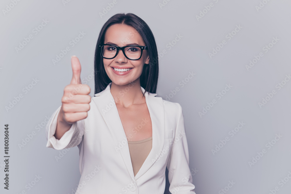 Close up portrait of caucasian gorgeous stunning charming lovely cute expert business lady, standing on pure light background, grinning, in black cool specs, shows finger up symbol Close up portrait of caucasian gorgeous stunning charming lovely cute expert business lady, standing on pure light background, grinning, in black cool specs, shows finger up symbol