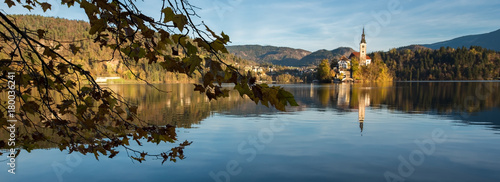 Panorama of church on island in the midlle of lake and  branchs with leaves photo