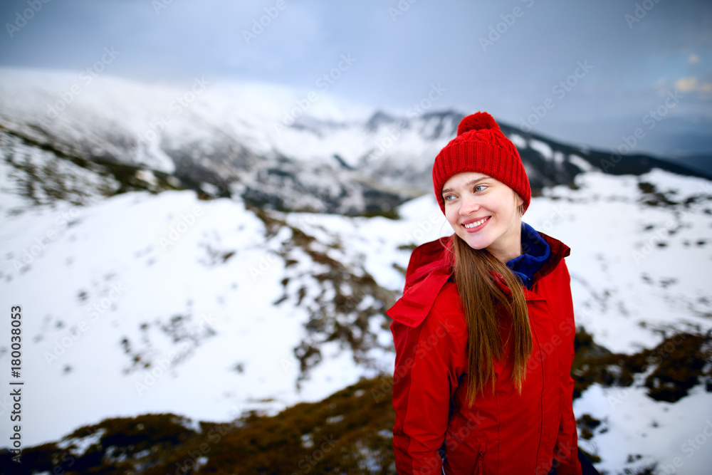 Portrait of a smiling happy woman. Shot of a young woman looking at the landscape while hiking in the mountains. Winter hiking