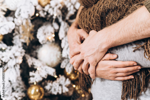 Hands close-up. Young happy couple near a Christmas tree. Christmas and New Year concept