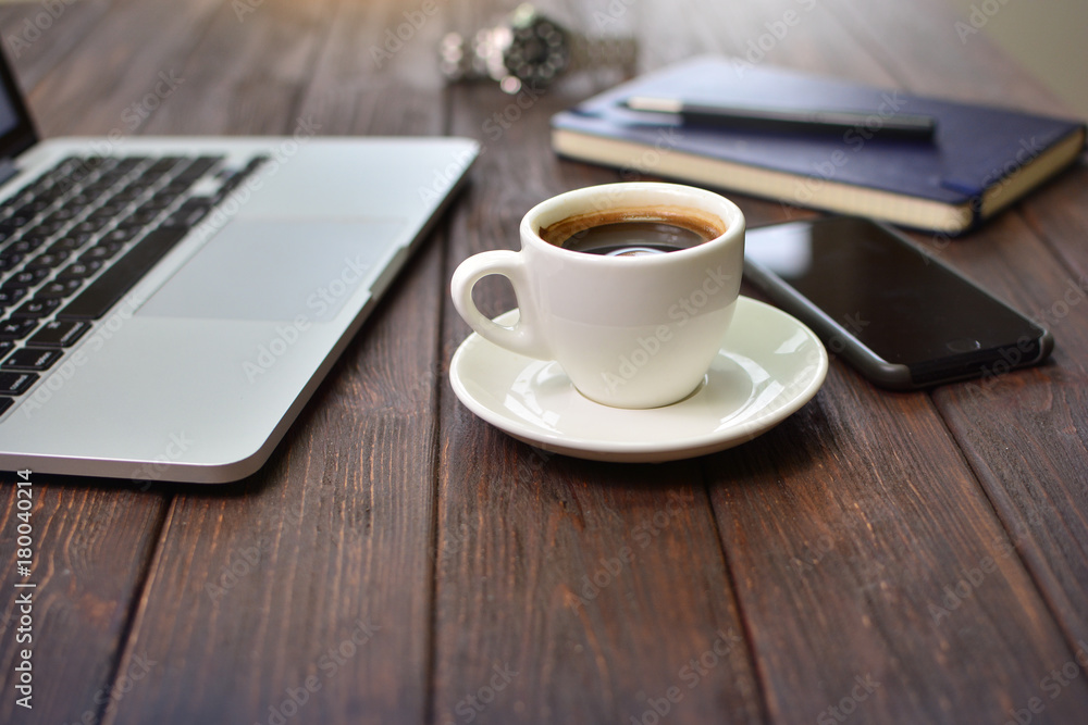 Cup of coffee on a office table near the laptop, phone and office chancery Cup of coffee on a office table near the laptop, phone and office chancery