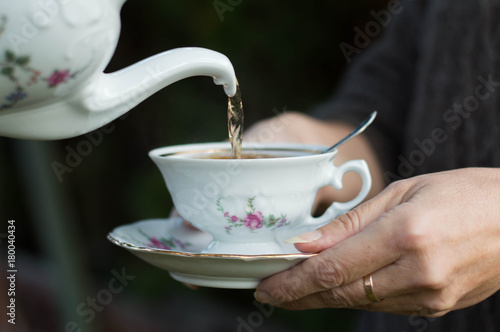 Closeup shot from hands holding a teacup and pouring tea