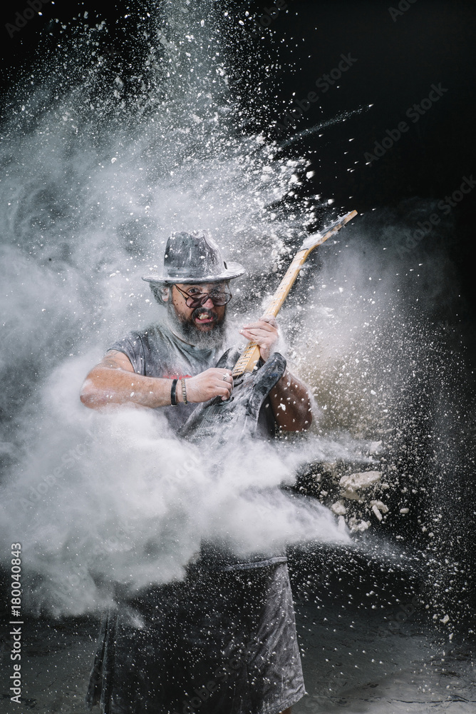 Obraz premium man with the guitar between chalk dust and smoke