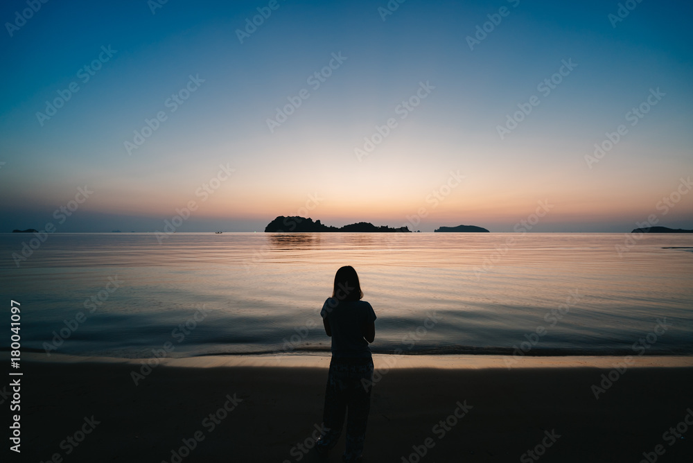 Young woman looking up to sunset sky.
