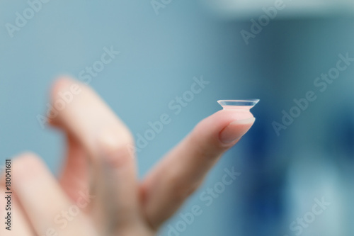 girl holds finger on a contact lens, closeup
