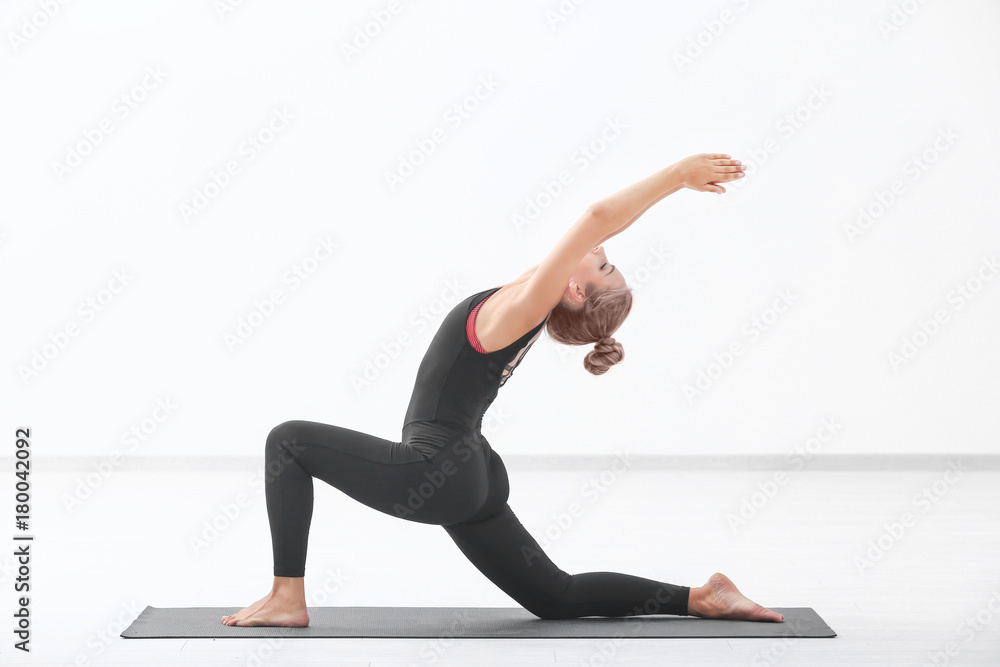Beautiful young woman practicing yoga indoors