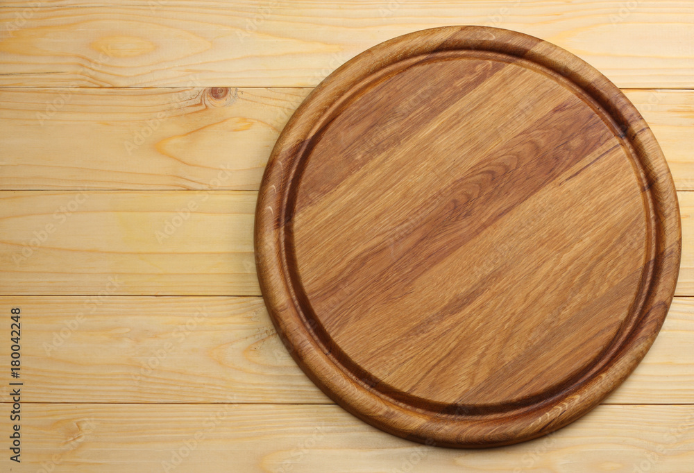 round wooden plate on light wooden background top view