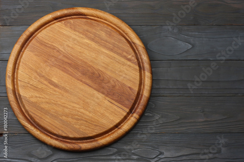 round wooden plate on dark wooden background top view