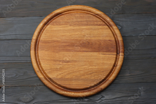round wooden plate on dark wooden background top view