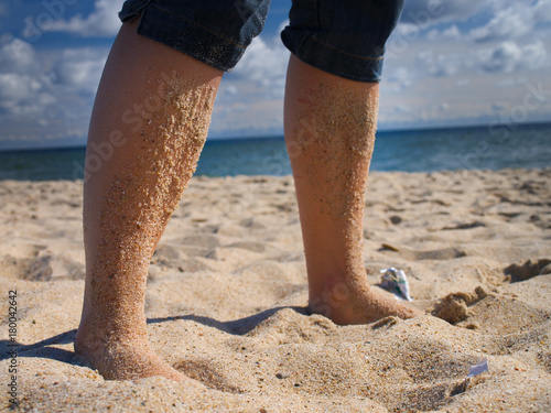human legs smeared with sea sand leaned against the stone