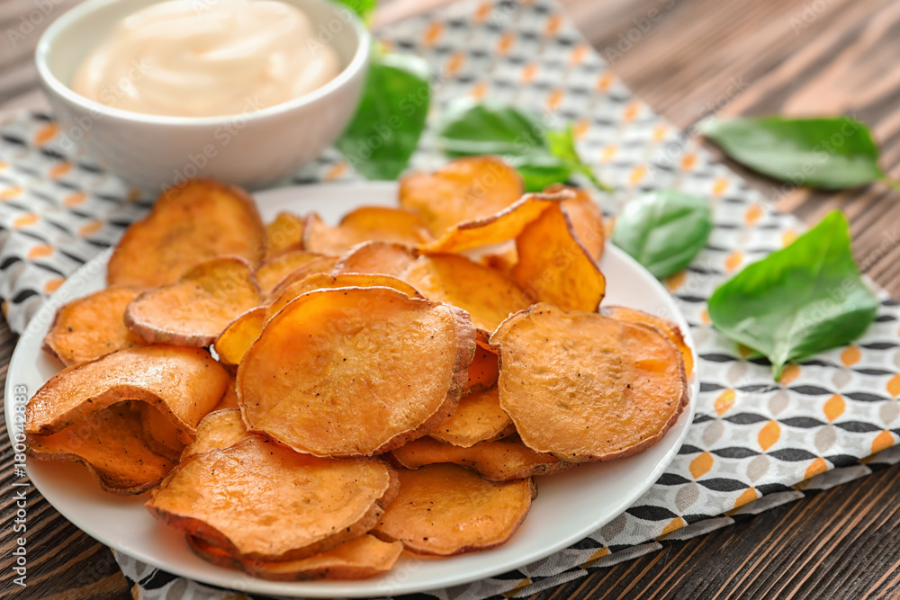 Plate with yummy sweet potato chips on table Plate with yummy sweet potato chips on table