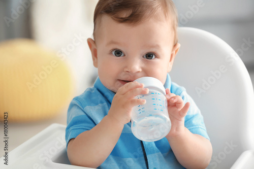 Cute baby drinking water indoors