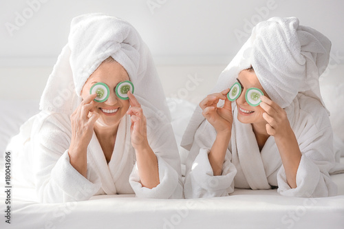 Mature woman using cosmetic eye mask pads with daughter at home photo