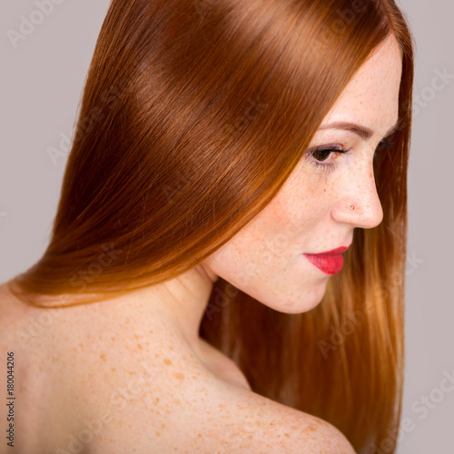 Portrait of a beautiful young woman with long red hair. Close-up photo in profile
