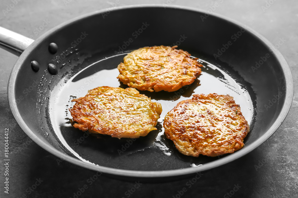Frying pan with Hanukkah potato pancakes on table Frying pan with Hanukkah potato pancakes on table