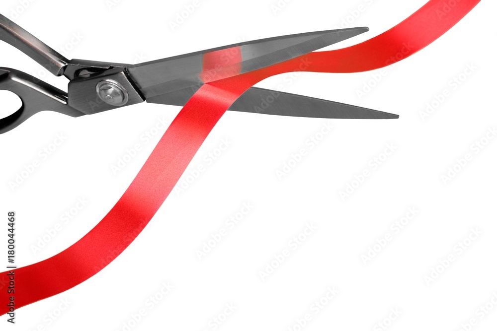 Scissors cutting red ribbon, close-up view on white background Scissors cutting red ribbon, close-up view on white background