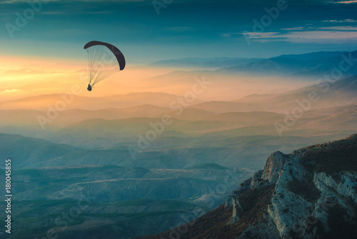 Silhouette of paraglider over the valley