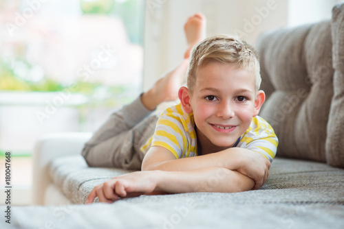 Happy schoolboy 9 years old lying on sofa