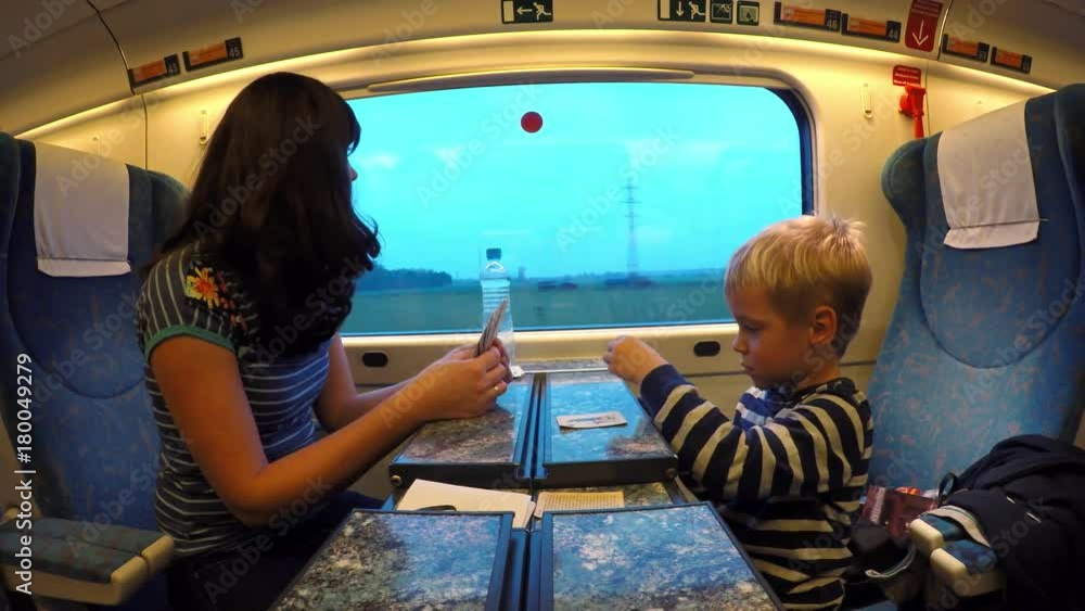 A young mother and her son travel by train. Woman and child playing ...
