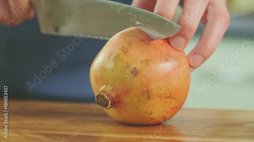 Man's Hands Cutting Pomegranate With Knife On Chopping Board