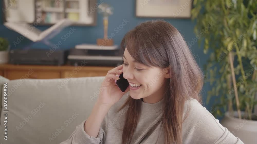 Cheerful Female Hipster Answering Smartphone On Sofa At Home Cheerful Female Hipster Answering Smartphone On Sofa At Home