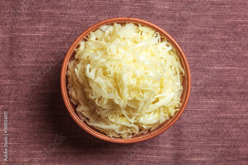 Sauerkraut in a clay plate, against a background of wooden boards
