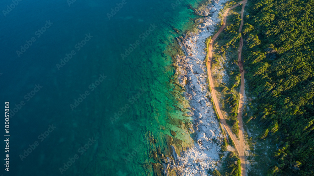 Fototapeta premium Drone shot of a rocky headland at daylight with emerald color water
