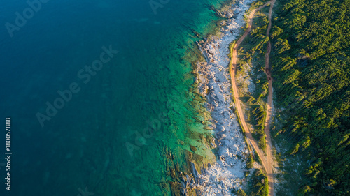 Drone shot of a rocky headland at daylight with emerald color water