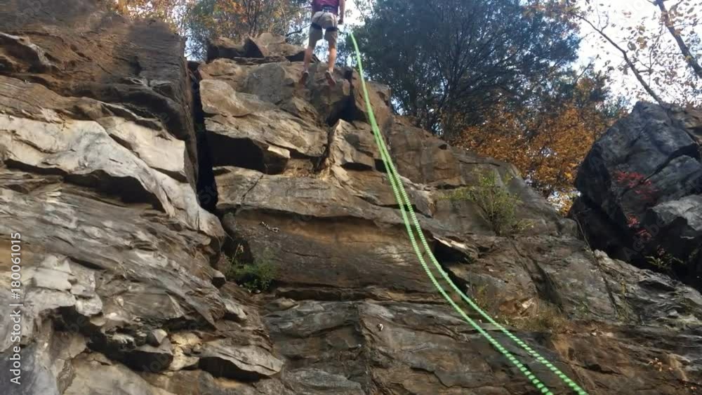 Man repelling down rock cliff from rock climbing in mountains Man repelling down rock cliff from rock climbing in mountains