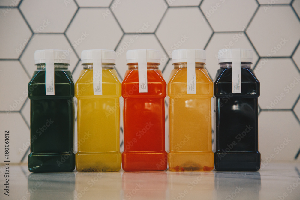 Detox diet pressed juice concept. Different fruit and vegetable organic juice on small plastic bottles on white texture background. Detox diet pressed juice concept. Different fruit and vegetable organic juice on small plastic bottles on white texture background.