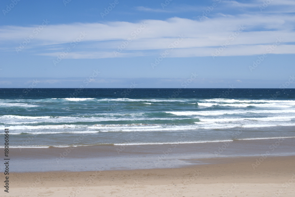 Beach and Ocean Waves Under Cloudy Blue Sky