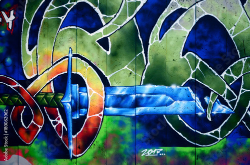 Fototapeta samoprzylepna Fragment szczegółowego graffiti rysunku wykonanego farbami w aerozolu na ścianie z betonowych płytek. Obraz tła sztuki ulicznej z bajkowym kryształowym mieczem