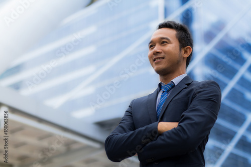 Asian young businessman standing cross one's arm and smiling confidently in a successful job. © Soonthorn